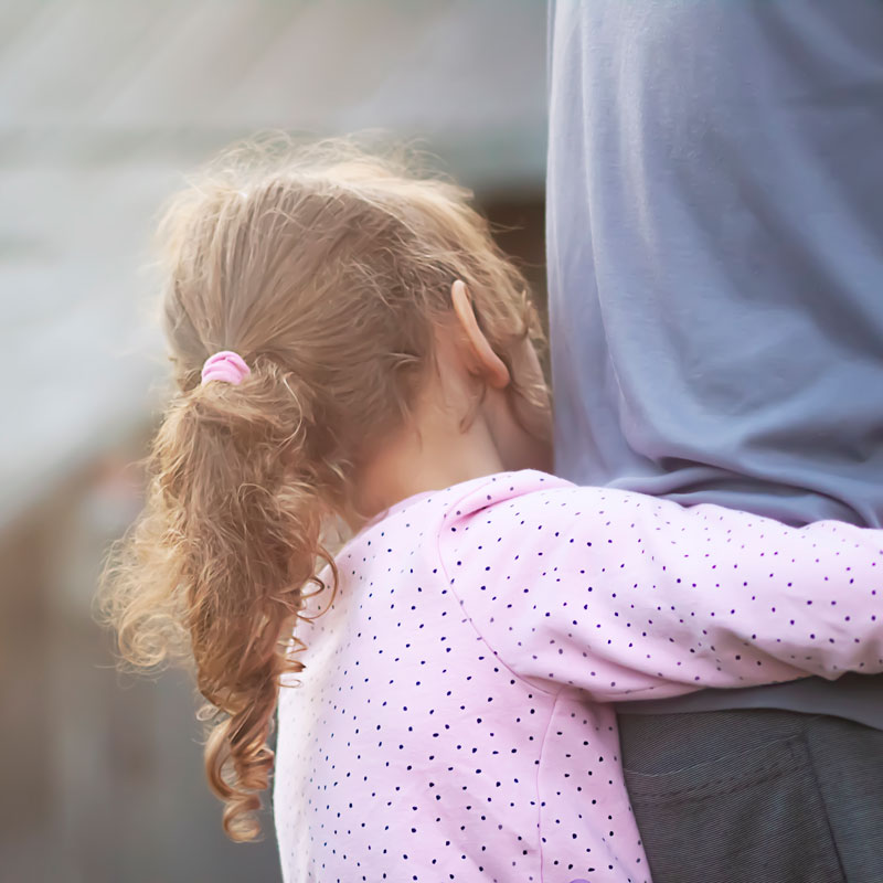 a young girl holding a parent around the waist representing child custody