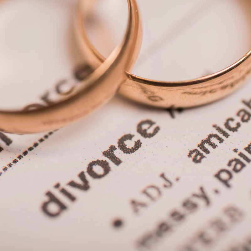 two wedding rings on top of divorce papers representing divorce